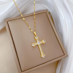 Detailed macro view of gold cross pendant with cubic zirconia on a flat link chain