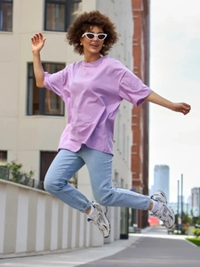 Υπαίθρια λήψη oversized λεβάντα βαμβακερό T-shirt με γαλάζιο τζιν παντελόνι