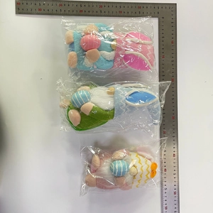 Vista de detalle de tres gnomos de Pascua con orejas de conejo y huevos en su envoltorio