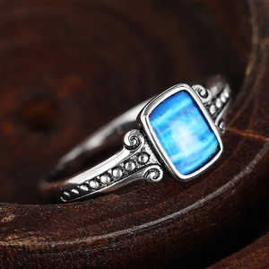 Macro shot of vintage silver ring with rectangular blue stone and scroll engraving