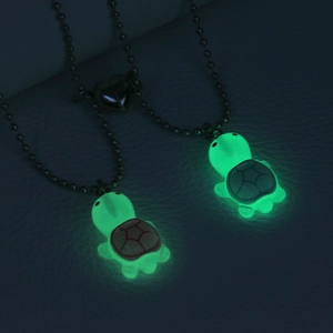Macro view of glowing green turtle pendants with heart magnetic clasp in dark environment