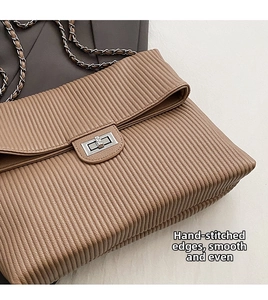 Close-up of vertical pleated leather handbag with silver metal clasp and chain strap