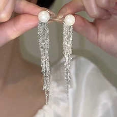 Detail showing white round pearls with elegant silver long fringe tassels on earrings