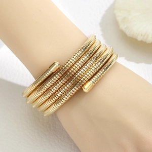 Detail of multi-layered gold spring coil bracelet on wrist with elegant texture