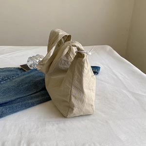 Minimalist beige pleated canvas tote bag for women shown in a modern lifestyle setting