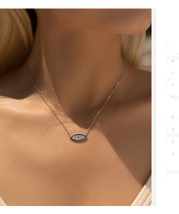 Detail of s925 silver evil eye necklace with blue zircons worn by a model in sunlight