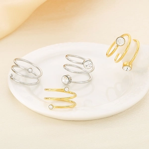 Detailed view of spiral stainless steel rings with round crystal accents in gold and silver