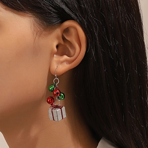 Close-up of model wearing Christmas earrings with red green bells and silver gift box charm