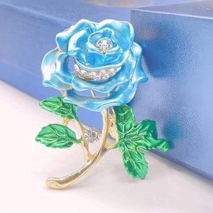 Elegant rose brooch with blue enamel petals, green leaves and sparkling crystals on gold alloy