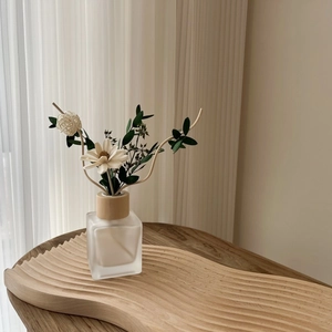 Minimalist reed diffuser set with frosted glass bottle and dried flowers on wooden tray
