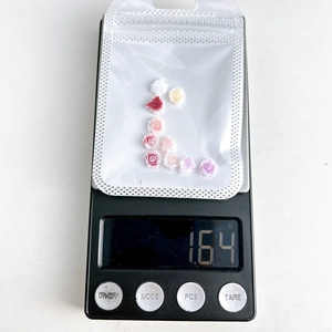 Macro shot of 3D resin rose nail art charms on a digital scale weighing 1.64g