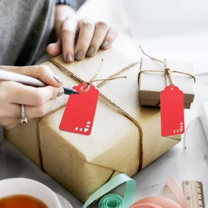 Macro view of writing on red gift tags with heart cutouts and jute twine for packaging