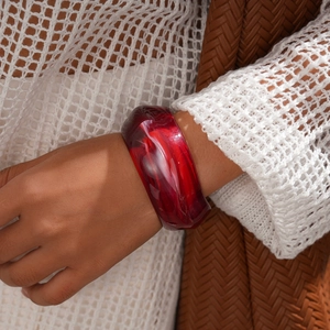 Close-up of a red acrylic bangle with marble pattern worn by a model in casual attire