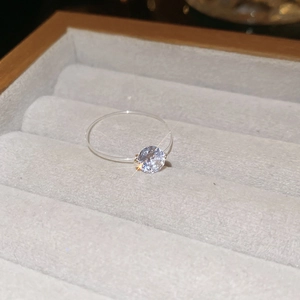 Detail of single round brilliant-cut zircon on a clear invisible band in a jewelry box