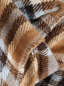 Gros plan d'un manteau en laine à carreaux marron et bleu montrant la texture et les coutures