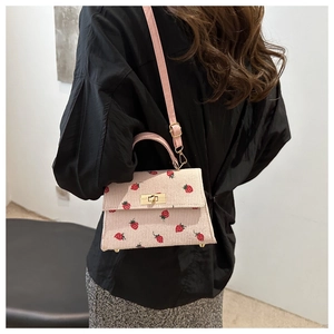 Close-up of pink corduroy small handbag featuring strawberry embroidery and gold clasp