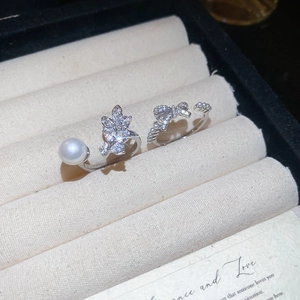Close-up of bow knot rings with pearls and sparkling zircon in a cream jewelry box