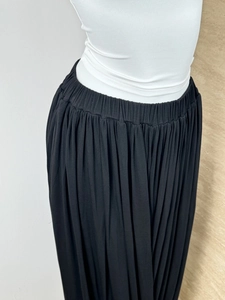 Detail of black pleated flowing skirt featuring elastic waistband on a fashion mannequin
