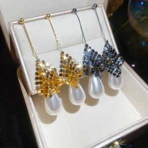 Detailed macro view of 18k gold plated drop earrings with pearls in a jewelry box