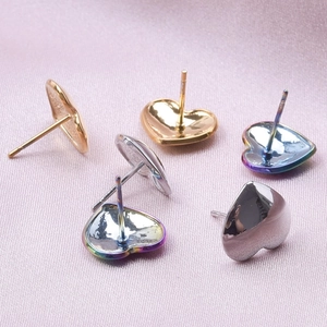 Macro shot of colorful stainless steel heart earrings on pink silk fabric background