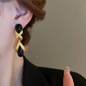 Detail of vintage teardrop earrings in black and gold resin on female model