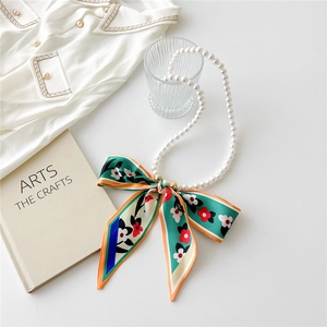 Detail of French vintage pearl necklace with a colorful floral silk scarf bow decoration
