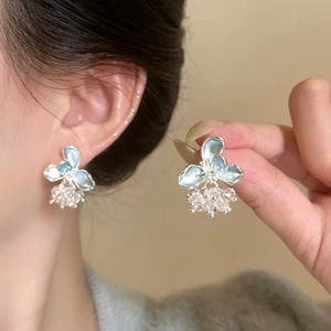 Close-up of light blue flower stud earrings featuring dangling crystal beads