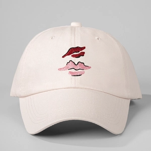 Macro detail of the red and pink lip embroidery on a light pink canvas baseball cap