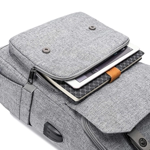 Front detail of grey oxford canvas backpack featuring functional pockets and metal buckles