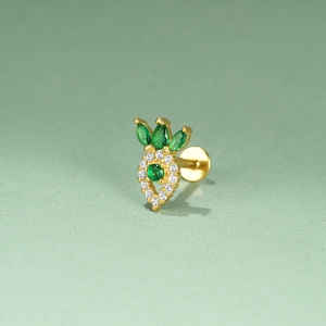 Macro detail of a golden pineapple stud earring with green and white cubic zirconia
