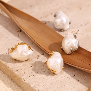 Macro detail of baroque pearls with gold and silver plated edges on a stone background