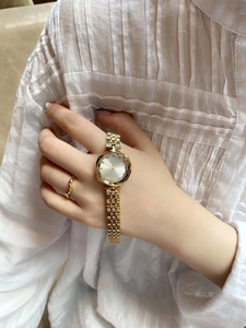 Detailed close-up of an elegant gold ladies' watch with a silver dial and crystal markers