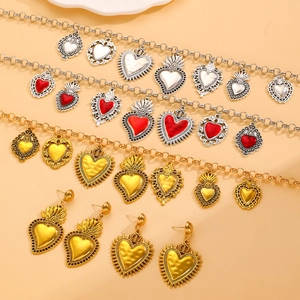 Macro detail of retro Sacred Heart jewelry sets with red enamel and silver flame textures