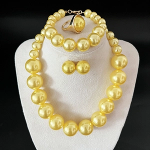 Golden pearl jewelry set including necklace, bracelet, earrings and ring on black background
