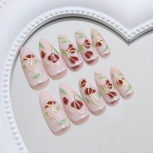 French vintage floral press-on nails with gold accents on almond shape pink base