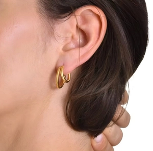 Nahaufnahme eleganter zweilagiger C-förmiger 18k Goldohrringe an einem Frauenohr
