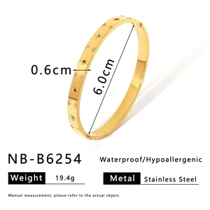 Macro view of gold stainless steel bangle with colorful crystals and star engraving