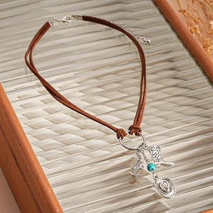 Detail of Western choker featuring brown suede cords with cactus, boot, and hat charms