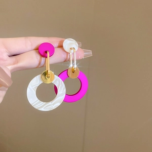 Detail of asymmetric acrylic hoop earrings with marble texture and rose red finish