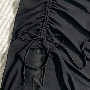 Close-up of black mesh fabric showing drawstring ruffle detail and bow tie on the beach skirt