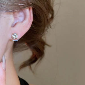 Close-up of a four-prong stud earring with a round-cut crystal on a model's ear