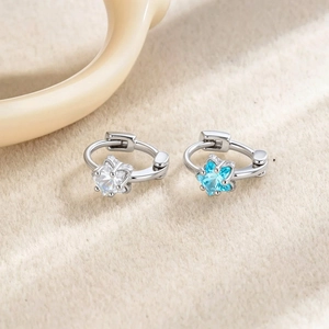 Elegant silver star hoop earrings with clear and blue zircon stones on a beige background