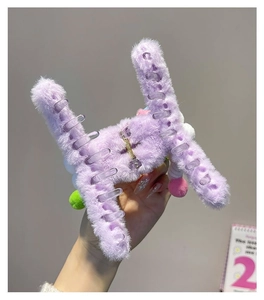Detail of purple plush claw clip with colorful pom-poms and soft fuzzy texture