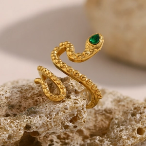 Detailed macro view of gold-plated snake ring with green teardrop stone eye