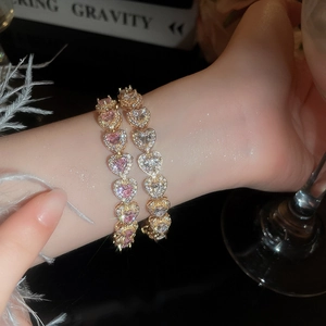 Close-up of pink and white heart-shaped tennis bracelets with gold-plated prong setting