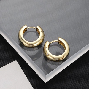Close-up of gold-plated hoop earrings featuring engraved stars and zircon stone details