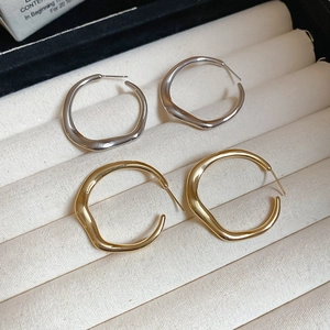 Detail view of irregular organic gold and silver hoop earrings on a velvet display