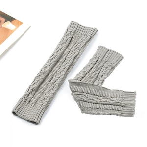Close-up of grey cable knit leg warmers with ribbed cuffs on white background