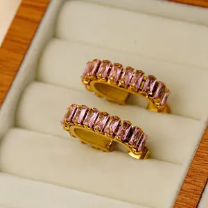 Chic gold U-shaped stud earrings with pink baguette-cut zircons on velvet display
