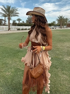 Close-up of beige ruffled chiffon dress with wide waist belt and brown fringe shoulder bag